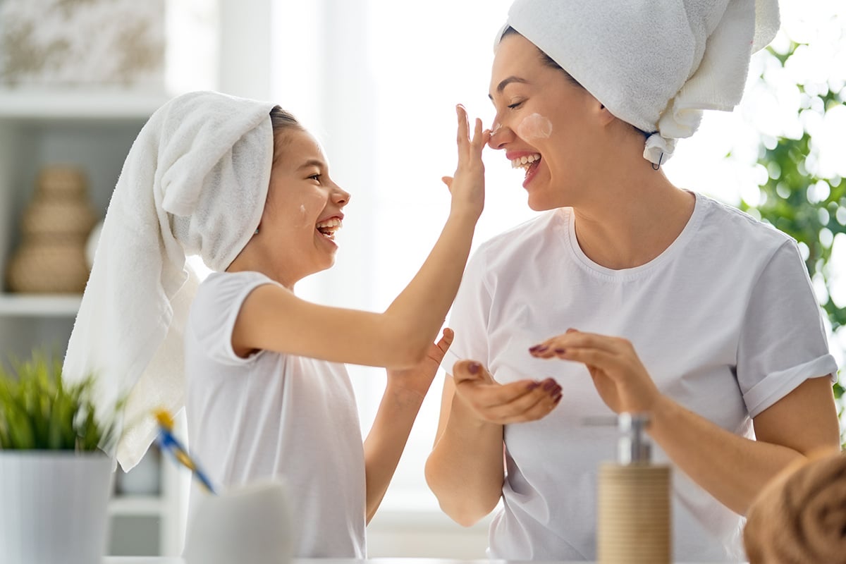Mother and daughter applying skin care products